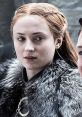 Sansa Stark from Game of Thrones, dressed in winter attire, displays a thoughtful expression amid a tense moment.