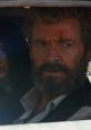 Logan, with a rugged look and scars, gazes intensely from a vehicle, embodying the iconic Wolverine character.