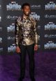 Chadwick Boseman at the Black Panther premiere, showcasing stylish attire and a vibrant smile on the purple carpet.