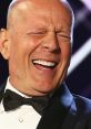 Bruce Willis laughing heartily, showcasing his joyful personality while dressed in a classic tuxedo.