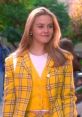 Cher in iconic yellow plaid outfit from Clueless, showcasing 90s fashion and confidence on a sunny day.