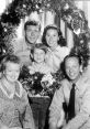 Cast of the Andy Griffith Show poses cheerfully around a festive Christmas wreath, showcasing holiday spirit and joy.