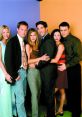 Iconic cast of Friends posing together, showcasing their unique styles and camaraderie in a colorful backdrop.