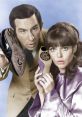 Max and 99 from "Get Smart" hold shoes with hidden gadgets, showcasing their comedic spy adventures and unique charm.