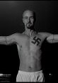 Character from American History X displays a Nazi swastika tattoo, symbolizing themes of hate and redemption.