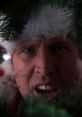 Intense scene from Christmas Vacation featuring a man in a Santa hat surrounded by greenery, capturing holiday chaos.