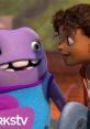 A purple alien smiles alongside a girl, capturing a heartwarming moment from the animated movie "Home.