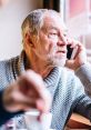 Elderly man on phone, reacting to conversation, possibly engaging with Lenny Telemarketer Time Wasting Robot.