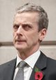 Malcolm Tucker's intense gaze in formal attire, embodying the sharp wit of "In The Loop" and "The Thick of It.