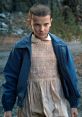 Eleven from Stranger Things, showcasing her intense expression and iconic outfit in a dramatic outdoor setting.