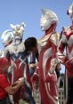 Ultraman characters in vibrant costumes being adjusted for a performance against a city backdrop, showcasing their iconic designs.