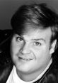 Black and white portrait of Chris Farley, showcasing his iconic smile and expressive eyes, exuding comedic charm.