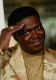 Bernie Mac smiling and saluting, wearing a stylish outfit with a gold chain, showcasing his charismatic personality.