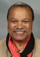 Billy Dee Williams smiles warmly, showcasing his iconic charm and style, wearing a colorful scarf around his neck.