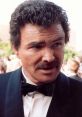 Burt Reynolds in a tuxedo at an awards ceremony, showcasing his iconic mustache and charming presence.