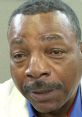 Close-up portrait of Carl Weathers, showcasing his expressive eyes and signature mustache, dressed in a stylish blazer.