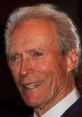 Clint Eastwood smiling warmly, showcasing his iconic silver hair and charming demeanor at a public event.