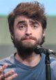 Daniel Radcliffe speaking passionately at a public event, microphone in hand, showcasing his expressive personality.