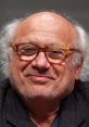 Danny DeVito smiling with glasses, showcasing his iconic look at a public event. Celebrated actor and filmmaker.