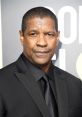 Denzel Washington looking sharp in a black suit at a public event, exuding confidence and charisma.