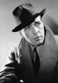 Classic black and white portrait of Humphrey Bogart in a stylish hat and coat, exuding 1940s Hollywood charm.