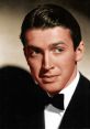 Classic portrait of James Stewart, showcasing his signature charm with a tuxedo and captivating blue eyes.