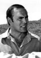 John Saxon in a dramatic pose, showcasing his intense expression, with a nature backdrop highlighting his acting charisma.