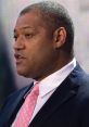 Laurence Fishburne speaking at an event, wearing a navy suit and pink tie, showcasing his leadership and charisma.