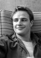 Young Marlon Brando smiles casually, showcasing his charisma in a relaxed setting. Iconic Hollywood star.