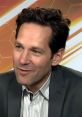 Paul Rudd smiling during an interview, dressed in a suit, showcasing his charismatic and charming personality.