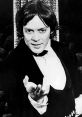 Raul Julia in a classic black and white portrait, exuding charm and charisma in formal attire.