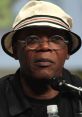 Samuel L. Jackson speaking at an event, wearing a stylish hat and glasses, showcasing his iconic presence and charisma.