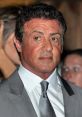 Sylvester Stallone at an event, wearing a stylish gray suit and tie, showcasing his iconic Hollywood presence.