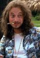 Lieutenant Dan Taylor with long hair and a playful expression, wearing a tropical shirt and holding a cigarette.