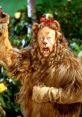 The Cowardly Lion with a red bow, expressing fear and vulnerability among a colorful, whimsical background.