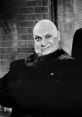 Uncle Fester with a mischievous grin, dressed in black, showcasing his iconic bald head and eccentric charm.