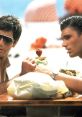 Tony Montana and friends enjoying drinks at a beach table in a memorable scene from Scarface (1983).