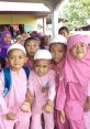 Group of cheerful children in pink uniforms and white caps, showcasing joy and friendship in a school setting.