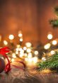 Christmas ornament with red ribbon, surrounded by festive lights and evergreen branches on a wooden surface.