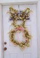 Spring-themed floral wreath on a white door, featuring delicate blossoms and a pink ribbon bow for decorative ideas.