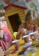 Two young girls engaged in creative play, painting with vibrant colors at a table, showcasing joy and artistic expression.