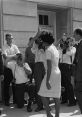 Historical moment capturing a woman surrounded by photographers, highlighting media attention on civil rights and racism.