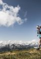 Mountain runner traversing a scenic trail with snowy peaks and blue skies, showcasing the thrill of outdoor running adventures.