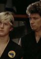 Johnny and his karate mentor look on during an intense moment in "The Karate Kid," showcasing their training journey.