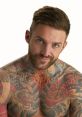 Aaron Chalmers, Geordie Shore star, showcasing his vibrant tattoo artwork and confident smile against a neutral background.