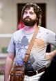 Alan Garner from "The Hangover" wearing a graphic tee and messenger bag, showcasing his quirky, laid-back style.