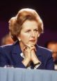 Margaret Thatcher in a blue suit, attentively listening at a conference, showcasing her iconic leadership style.