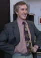 Alan Partridge smiling confidently in a suit, iconic moment from "I'm Alan Partridge," showcasing his humorous character.