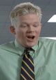 Drew from Office Space with surprised expression, wearing a green shirt and striped tie in a corporate setting.