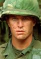 Sgt. Barnes from Platoon, showcasing a battle-hardened expression in military gear amidst a jungle setting.